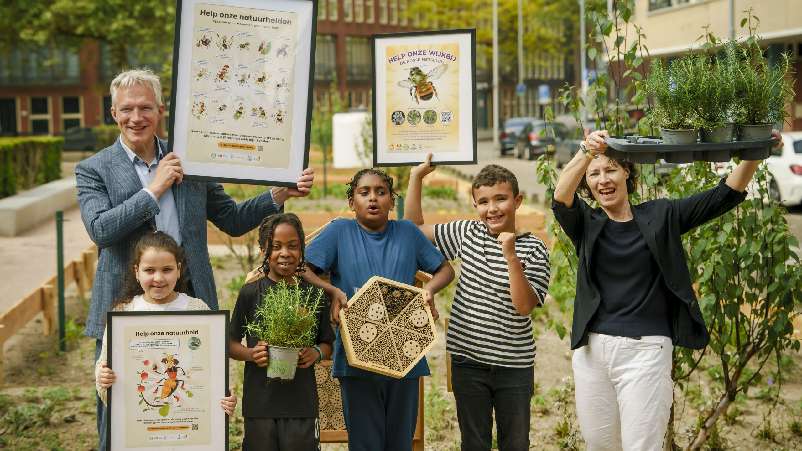 Berend Potjer, Ingeborg berger en vier kinderen uit bospolder poseren met rozemarijnplanten, bijenhotel en wijkbijenposters