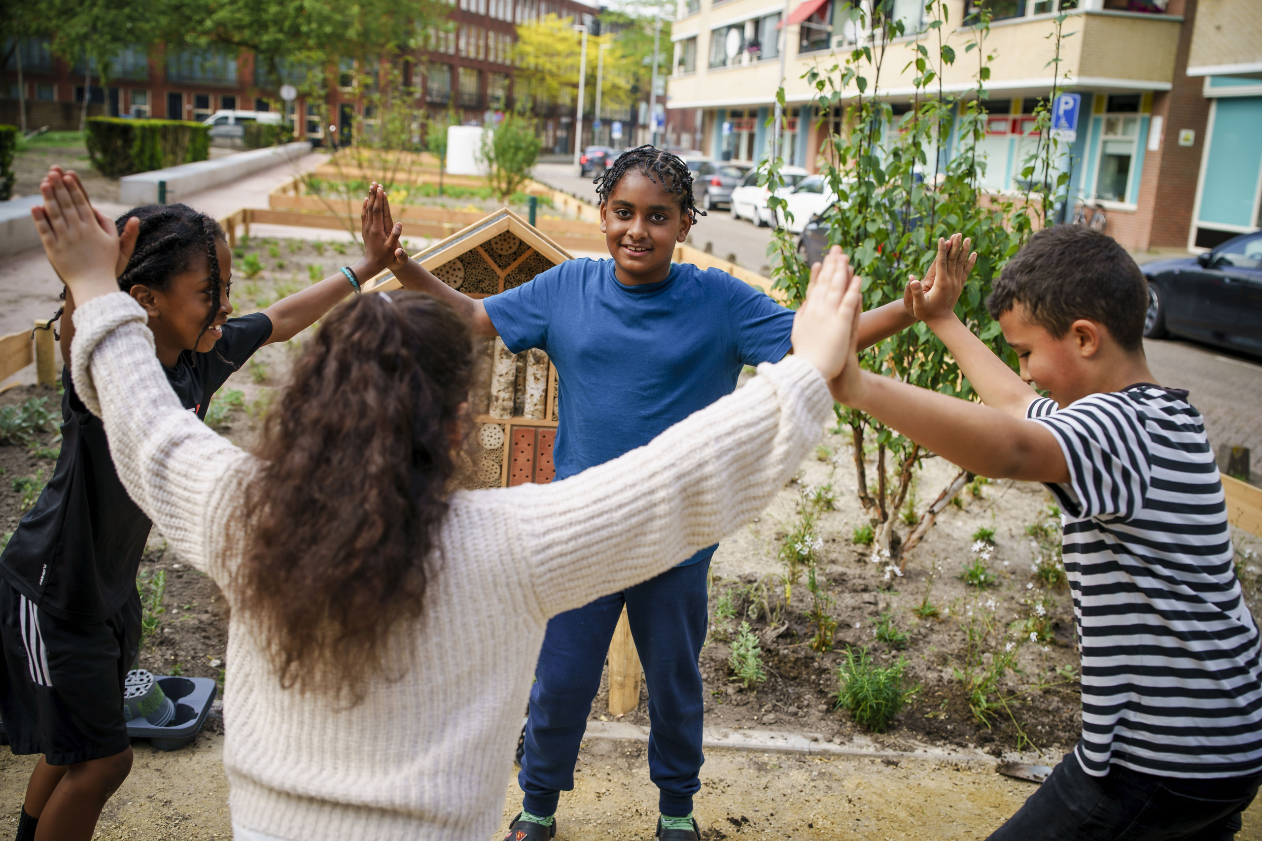 4 kinderen maken een kring bij de nieuwe bloemperken op het Bospolderplein in Rotterdam