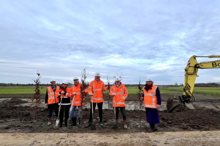 poserende mensen in werktenu met schep en boompjes om te planten.