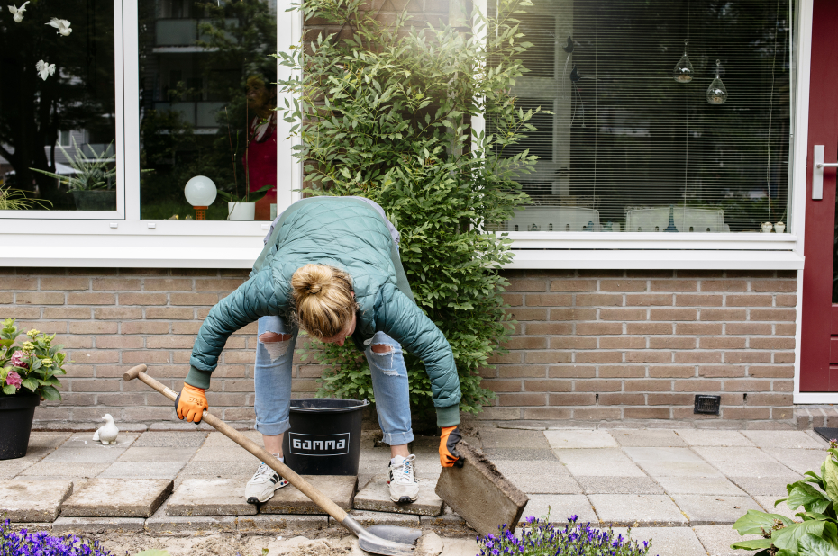 Vrouw verwijdert stoeptegels voor een huis