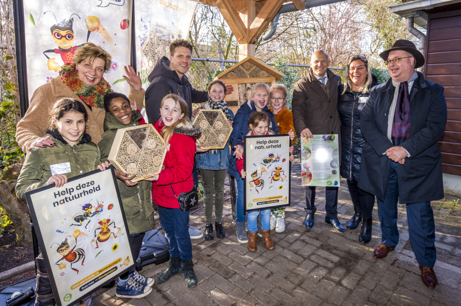 gRoep mensen (volwassenen en kinderen) met bijenhotels en Natuurhelden-posters bij start van een bijencampagne