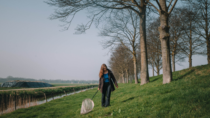 Linde Slikboer met een insectennet  op een dijk