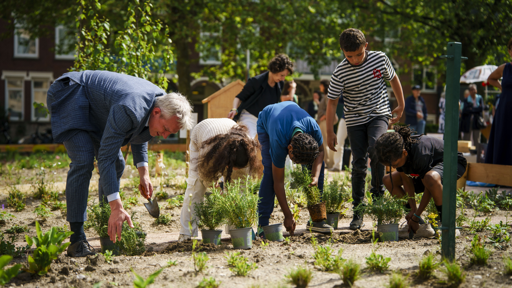Kinderen en gedeputeerde planten bijenplanten bij de start van de wijkbijencampange 2024