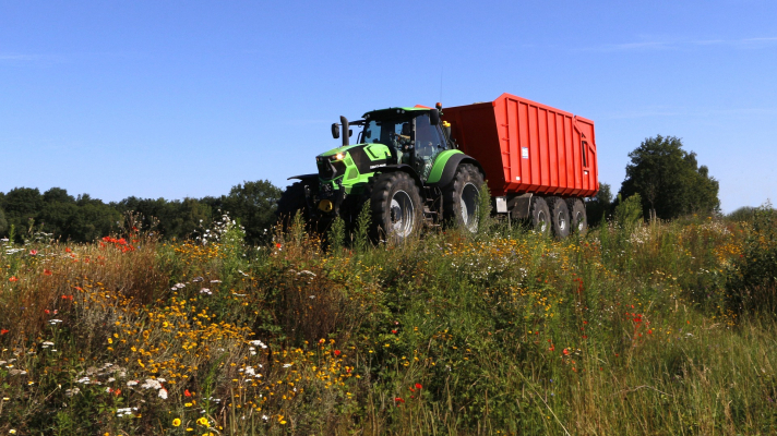 tractor rijdt langs bloemrijke berm
