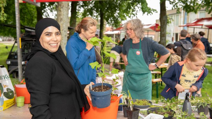 Vrouw met stekje bij kraam op ontdekmarkt 